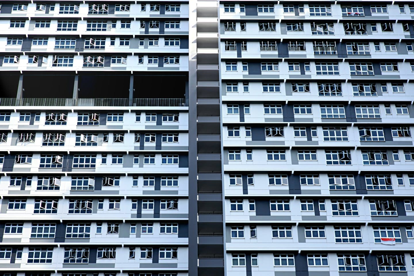 Nowoczesny budynek mieszkalny z białymi i szarymi geometrycznymi panelami.